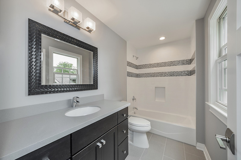 Example of a mid-sized transitional 3/4 gray tile and mosaic tile porcelain tile bathroom design in Chicago with recessed-panel cabinets, dark wood cabinets, a two-piece toilet, gray walls, an undermount sink and quartz countertops