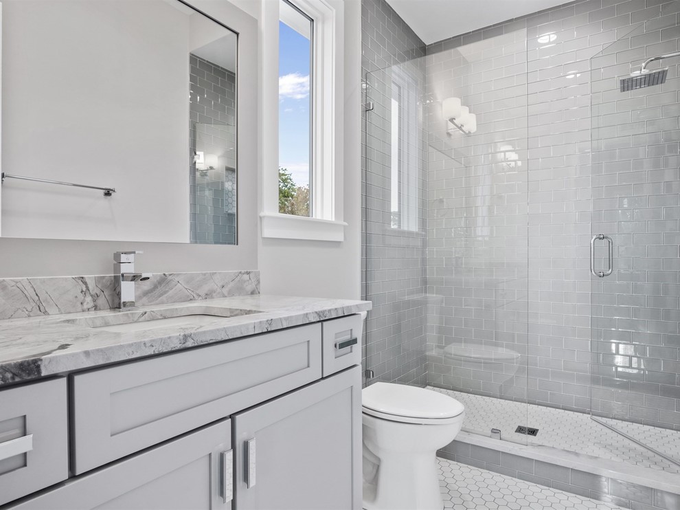 Example of a mid-sized transitional 3/4 gray tile and subway tile ceramic tile and white floor alcove shower design in Orlando with shaker cabinets, gray cabinets, a one-piece toilet, gray walls, an undermount sink, marble countertops, a hinged shower door and gray countertops