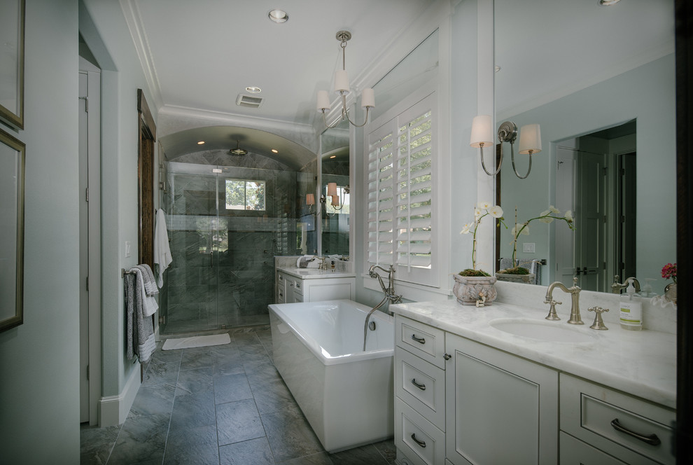 Réalisation d'une grande douche en alcôve principale design avec un lavabo encastré, un placard à porte affleurante, des portes de placard blanches, un plan de toilette en marbre, une baignoire indépendante, un carrelage gris et un mur marron.
