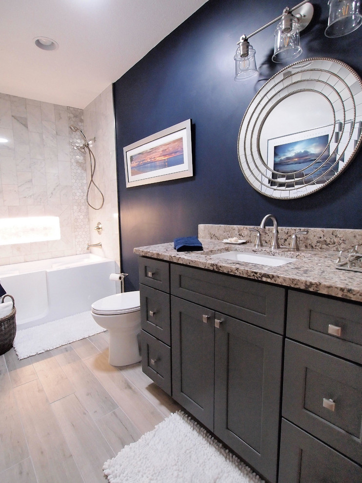 Inredning av ett klassiskt litet badrum med dusch, med skåp i shakerstil, grå skåp, ett badkar i en alkov, en dusch/badkar-kombination, en toalettstol med hel cisternkåpa, vit kakel, mosaik, blå väggar, vinylgolv, ett undermonterad handfat och granitbänkskiva