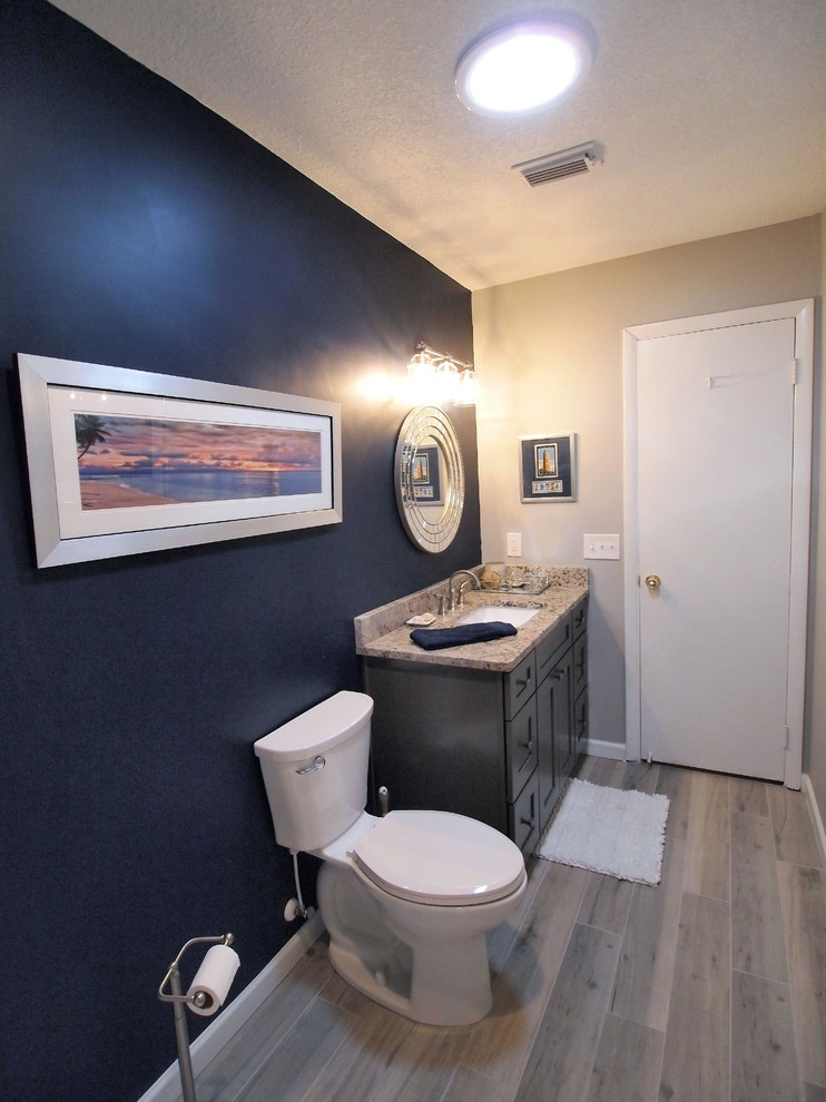Klassisk inredning av ett litet toalett, med skåp i shakerstil, grå skåp, en toalettstol med hel cisternkåpa, vit kakel, mosaik, blå väggar, vinylgolv, ett undermonterad handfat och granitbänkskiva