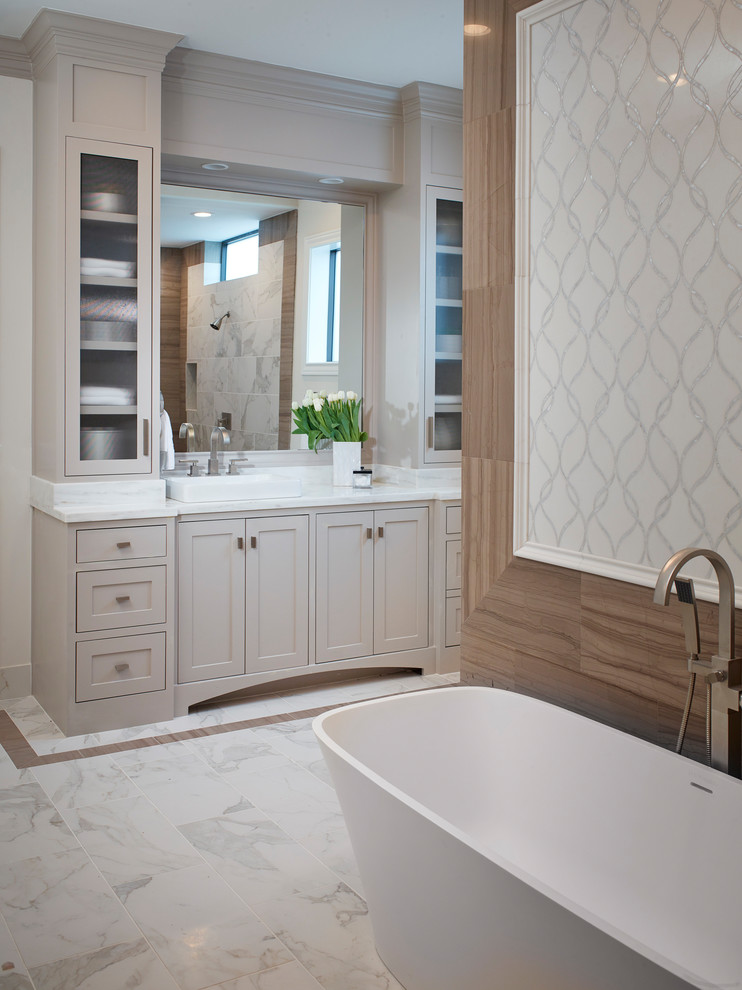 На фото: главная ванная комната в классическом стиле с фасадами в стиле шейкер, серыми фасадами, отдельно стоящей ванной, мраморным полом, настольной раковиной и белым полом
