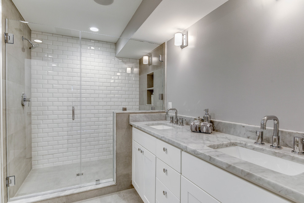 На фото: большая главная ванная комната в стиле неоклассика (современная классика) с фасадами в стиле шейкер, белыми фасадами, душем в нише, унитазом-моноблоком, белой плиткой, плиткой кабанчик, серыми стенами, врезной раковиной и мраморной столешницей