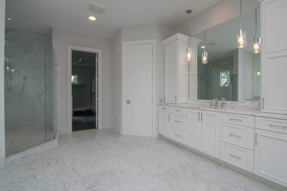 Cette image montre une grande salle de bain principale traditionnelle avec un placard avec porte à panneau encastré, des portes de placard blanches, une baignoire indépendante, une douche d'angle, un carrelage gris, un carrelage blanc, des dalles de pierre, un mur blanc, un sol en marbre, un lavabo suspendu, un plan de toilette en marbre, un sol gris et une cabine de douche à porte battante.