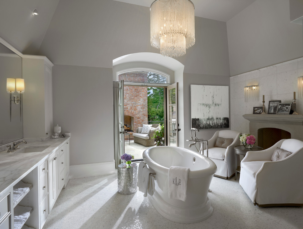 На фото: ванная комната в классическом стиле с врезной раковиной, фасадами в стиле шейкер, белыми фасадами, отдельно стоящей ванной, белой плиткой, серыми стенами и полом из мозаичной плитки