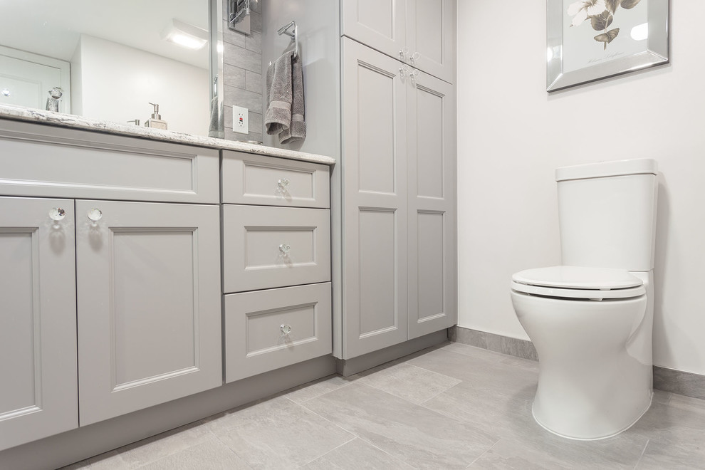Bathroom - large transitional master gray tile and porcelain tile porcelain tile and gray floor bathroom idea in DC Metro with shaker cabinets, gray cabinets, a two-piece toilet, gray walls, an undermount sink, granite countertops, a hinged shower door and white countertops