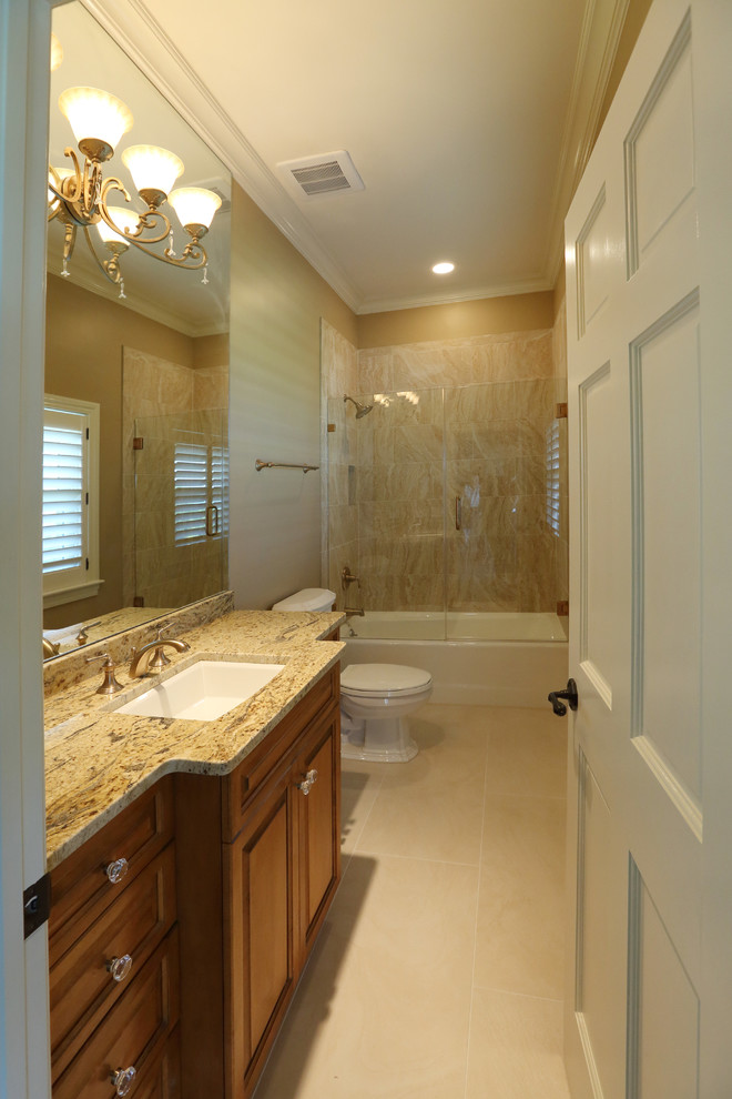 Inspiration for a medium sized mediterranean bathroom in Tampa with raised-panel cabinets, medium wood cabinets, a walk-in shower, a one-piece toilet, beige tiles, brown tiles, grey tiles, stone tiles, beige walls, marble flooring, a submerged sink, granite worktops and an alcove bath.