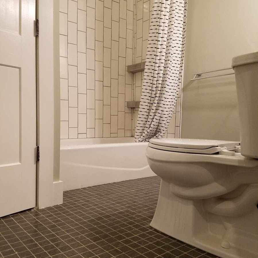 Inspiration for a small traditional ensuite bathroom in Philadelphia with shaker cabinets, dark wood cabinets, a built-in bath, a shower/bath combination, a two-piece toilet, white tiles, metro tiles, grey walls, slate flooring, an integrated sink, solid surface worktops, blue floors and a shower curtain.