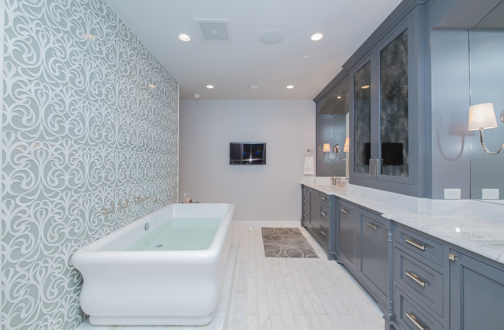 Large transitional master white tile and stone tile medium tone wood floor freestanding bathtub photo in Austin with recessed-panel cabinets, gray cabinets, beige walls, an undermount sink and marble countertops