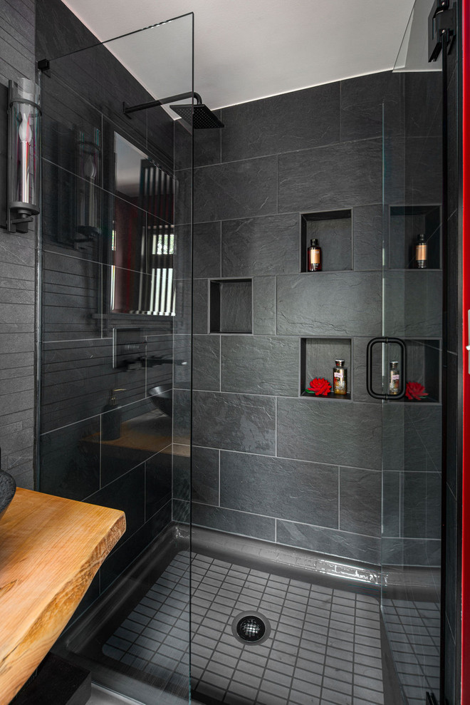 Cette photo montre une petite salle de bain chic avec WC à poser, un carrelage noir, des carreaux de porcelaine, un mur rouge, un sol en vinyl, une vasque, un plan de toilette en bois, un sol gris, une cabine de douche à porte battante et un plan de toilette marron.