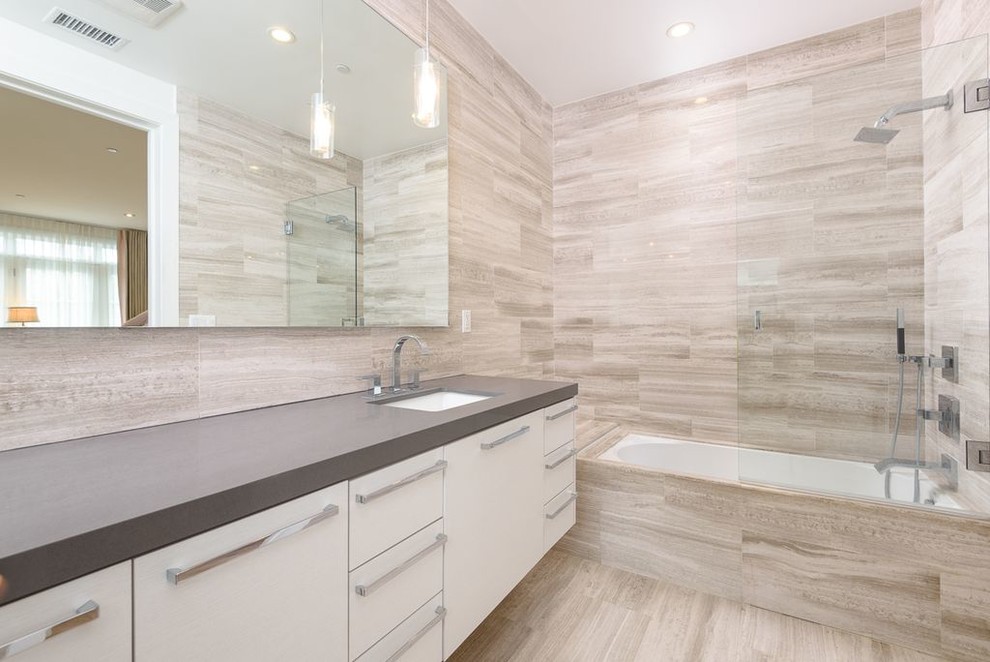 This is an example of a large traditional shower room bathroom in Other with flat-panel cabinets, white cabinets, an alcove bath, a shower/bath combination, a two-piece toilet, grey tiles, stone tiles, white walls, light hardwood flooring, a built-in sink, solid surface worktops, beige floors, an open shower and grey worktops.