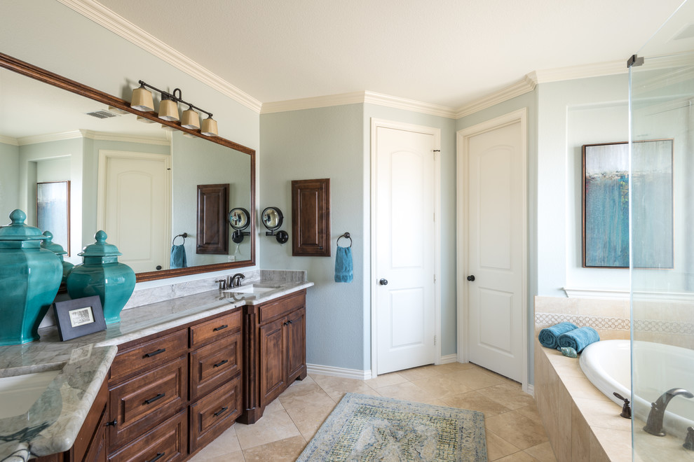 Пример оригинального дизайна: главная ванная комната среднего размера в стиле неоклассика (современная классика) с фасадами с выступающей филенкой, фасадами цвета дерева среднего тона, накладной ванной, угловым душем, плиткой из травертина, синими стенами, полом из травертина, врезной раковиной, столешницей из гранита, бежевым полом и душем с распашными дверями