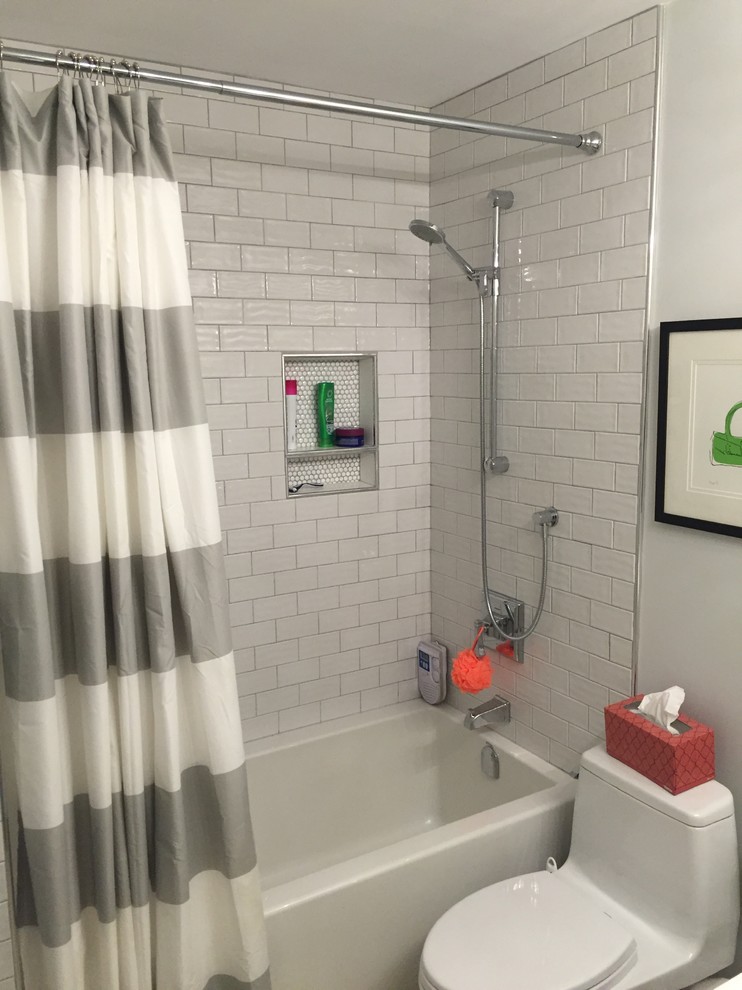 Klassisk inredning av ett badrum, med ett badkar i en alkov, en dusch/badkar-kombination, en toalettstol med hel cisternkåpa, vit kakel, tunnelbanekakel, vita väggar, klinkergolv i småsten, vita skåp och dusch med duschdraperi