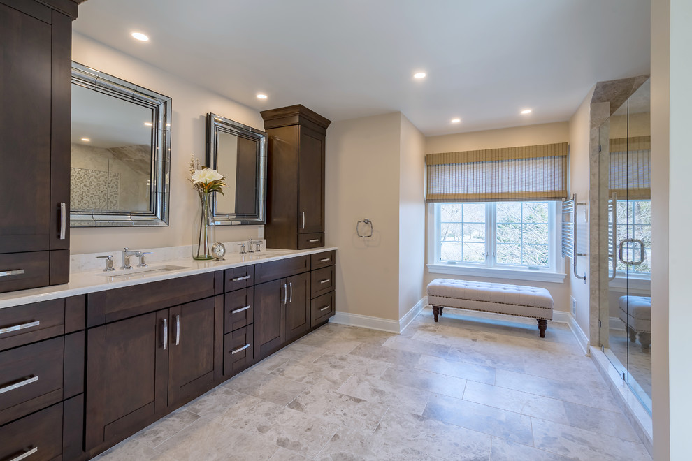 Inspiration for a transitional master multicolored tile and travertine tile travertine floor and brown floor bathroom remodel in Other with shaker cabinets, dark wood cabinets, beige walls, quartzite countertops, a hinged shower door, white countertops and a wall-mount toilet