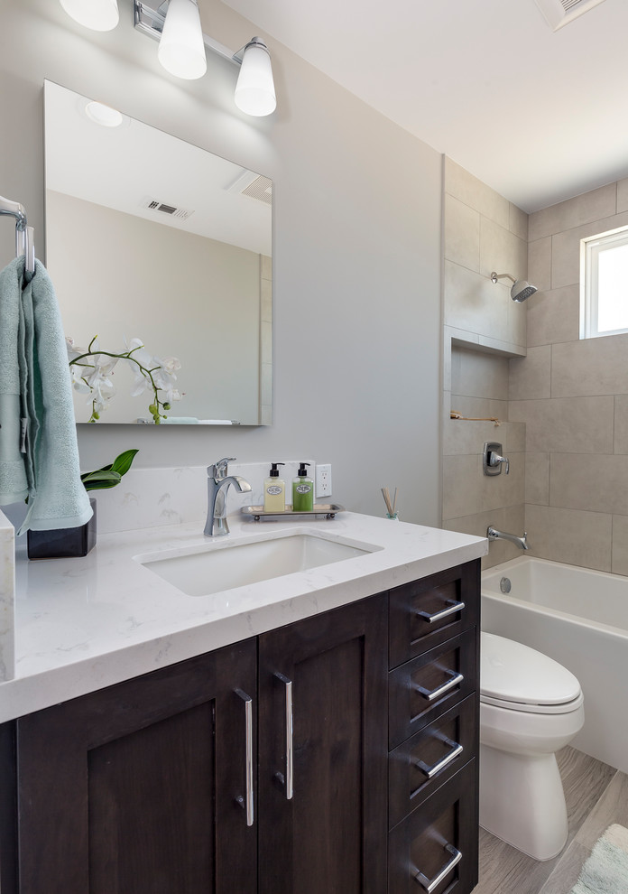 Example of a mid-sized transitional gray tile and porcelain tile porcelain tile and gray floor bathroom design in Los Angeles with shaker cabinets, dark wood cabinets, a two-piece toilet, gray walls, an undermount sink and quartz countertops