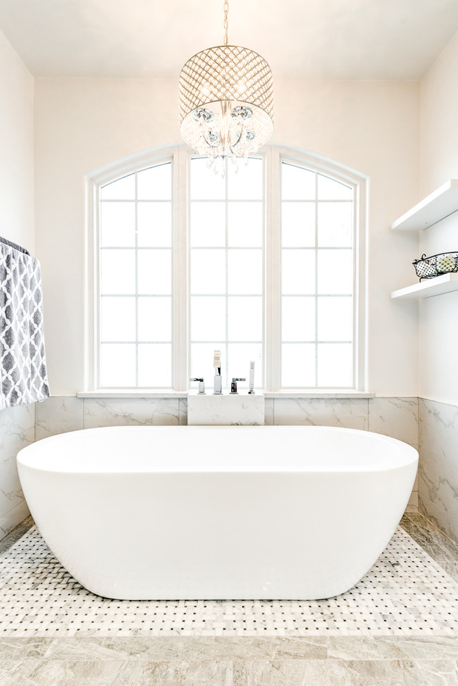 Идея дизайна: большая ванная комната в стиле неоклассика (современная классика) с белыми фасадами, гидромассажной ванной, угловым душем, мраморной плиткой, белыми стенами, полом из керамогранита, накладной раковиной, серым полом и душем с распашными дверями