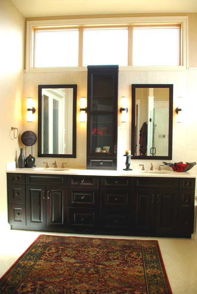 Пример оригинального дизайна: огромная главная ванная комната в стиле неоклассика (современная классика) с фасадами с выступающей филенкой, темными деревянными фасадами, коричневой плиткой, плиткой из травертина, желтыми стенами, полом из травертина, врезной раковиной и столешницей из кварцита