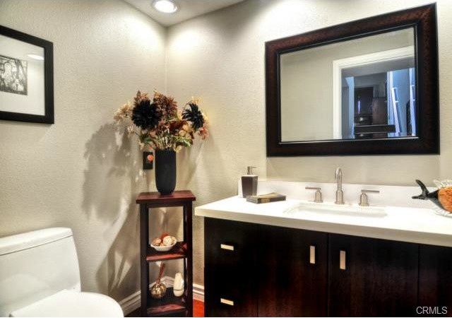 Cette photo montre une salle de bain chic en bois foncé de taille moyenne avec un placard à porte shaker, WC séparés, un sol en bois brun, un lavabo encastré et un plan de toilette en quartz modifié.