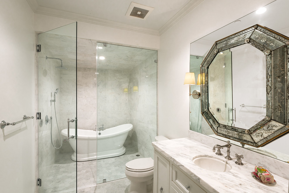 Transitional white tile and marble tile marble floor bathroom photo in San Francisco with recessed-panel cabinets, white cabinets, a one-piece toilet, white walls, an undermount sink, marble countertops, a hinged shower door and white countertops