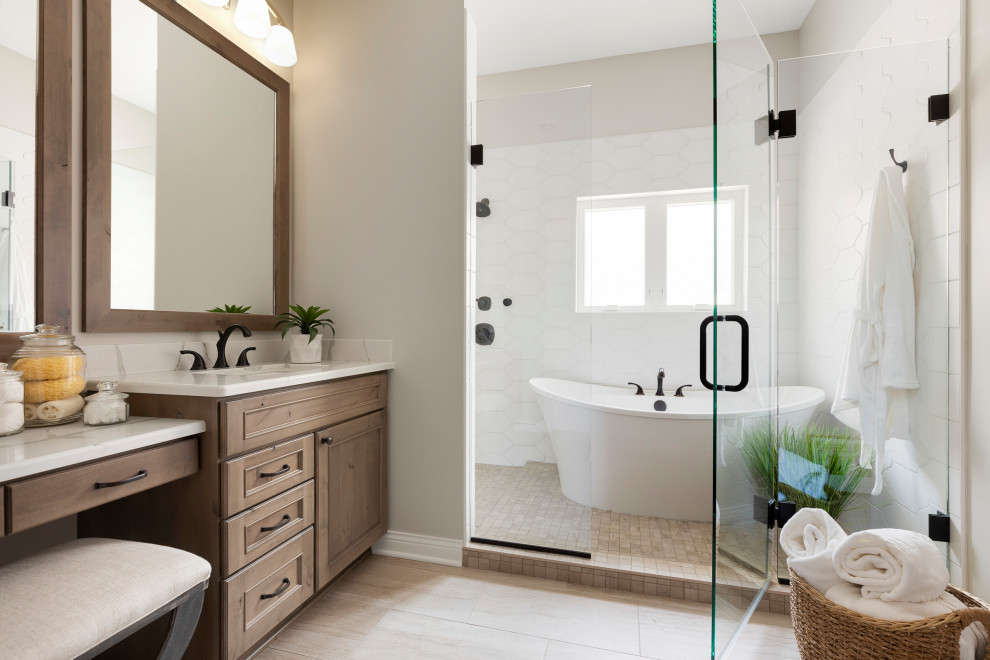 Klassisk inredning av ett stort vit vitt en-suite badrum, med skåp i mellenmörkt trä, ett fristående badkar, våtrum, vit kakel, grå väggar, ljust trägolv, ett undermonterad handfat, beiget golv, dusch med gångjärnsdörr och luckor med infälld panel