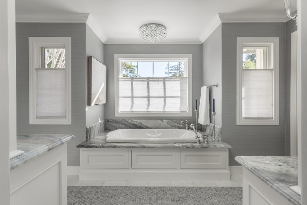 Klassisk inredning av ett mellanstort grå grått en-suite badrum, med luckor med infälld panel, vita skåp, ett platsbyggt badkar, grå kakel, porslinskakel, grå väggar, klinkergolv i porslin, ett undermonterad handfat, marmorbänkskiva och vitt golv
