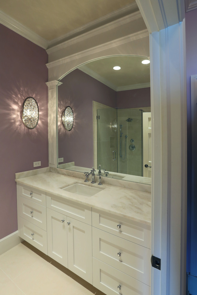 Cette image montre une salle d'eau méditerranéenne de taille moyenne avec un placard avec porte à panneau encastré, des portes de placard blanches, une douche ouverte, WC à poser, un carrelage beige, un carrelage blanc, un carrelage de pierre, un mur violet, un sol en linoléum, un lavabo encastré et un plan de toilette en marbre.