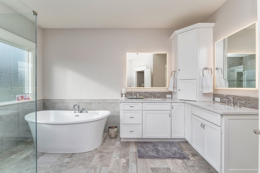 Example of a mid-sized transitional master gray tile and porcelain tile porcelain tile and gray floor bathroom design in Boise with shaker cabinets, white cabinets, a two-piece toilet, gray walls, an undermount sink, quartz countertops and a hinged shower door