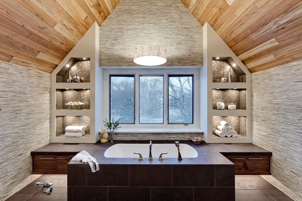 Imagen de cuarto de baño contemporáneo con armarios con paneles lisos, puertas de armario de madera en tonos medios, bañera encastrada sin remate, baldosas y/o azulejos grises, azulejos en listel y piedra