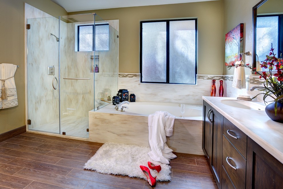 Klassisk inredning av ett en-suite badrum, med ett undermonterad handfat, skåp i shakerstil, skåp i mörkt trä, bänkskiva i akrylsten, ett platsbyggt badkar, brun kakel, porslinskakel, beige väggar och klinkergolv i porslin