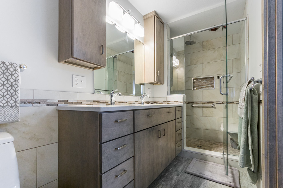 Example of a mid-sized transitional master beige tile and ceramic tile ceramic tile doorless shower design in Chicago with flat-panel cabinets, gray cabinets, a one-piece toilet, gray walls, an integrated sink and quartz countertops