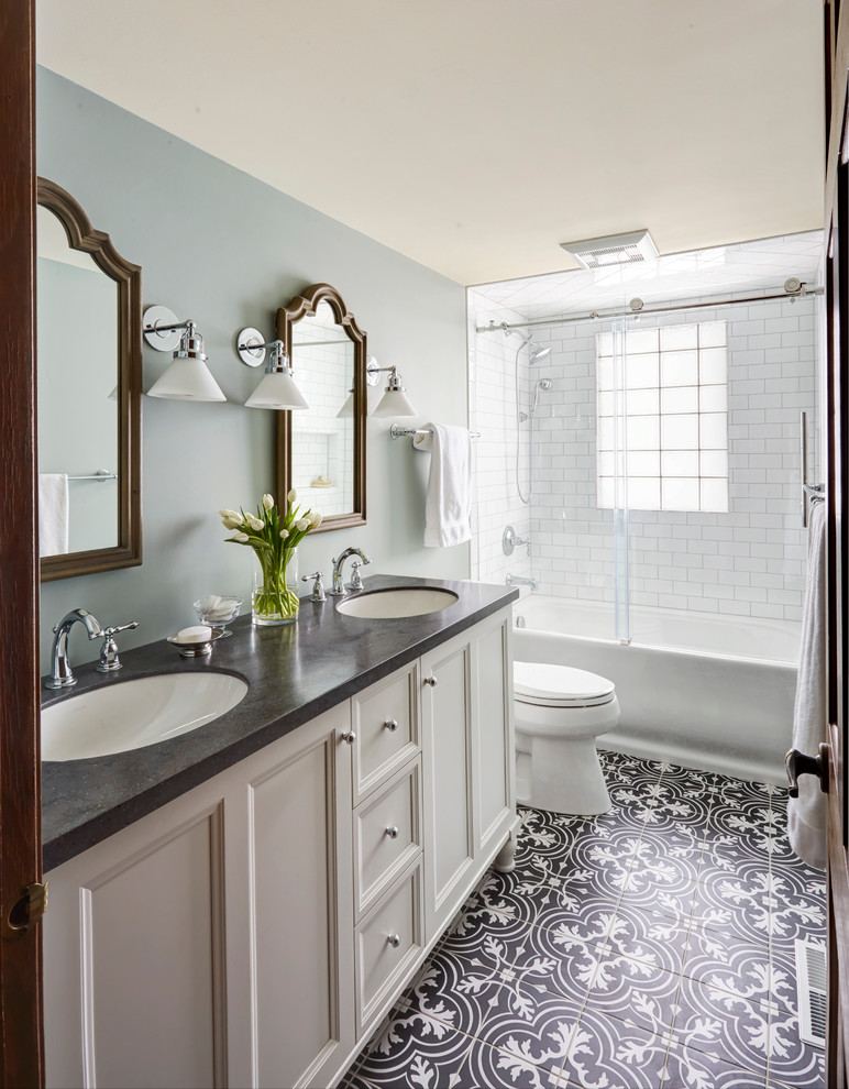 This is an example of a medium sized classic bathroom in Chicago with white cabinets, an alcove bath, a shower/bath combination, a two-piece toilet, white tiles, metro tiles, blue walls, mosaic tile flooring, a submerged sink and solid surface worktops.