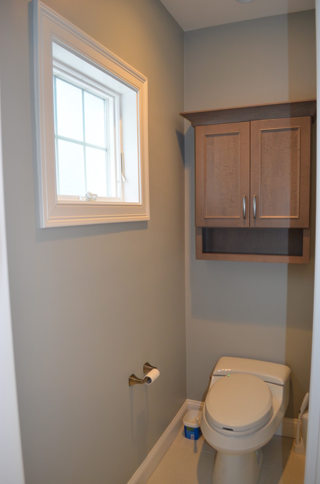 Powder room - mid-sized transitional brown tile, gray tile and matchstick tile porcelain tile and beige floor powder room idea in Boston with an undermount sink, recessed-panel cabinets, quartz countertops, medium tone wood cabinets, a one-piece toilet and gray walls
