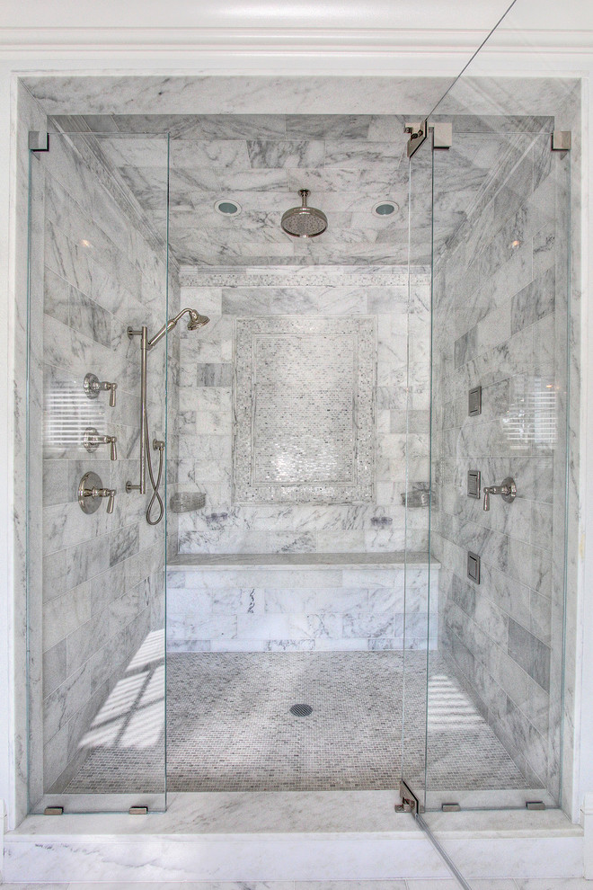 Cette photo montre une grande douche en alcôve principale chic avec un lavabo encastré, un placard avec porte à panneau encastré, des portes de placard blanches, un plan de toilette en marbre, une baignoire indépendante, un carrelage gris, un mur gris, un sol en marbre et un carrelage de pierre.