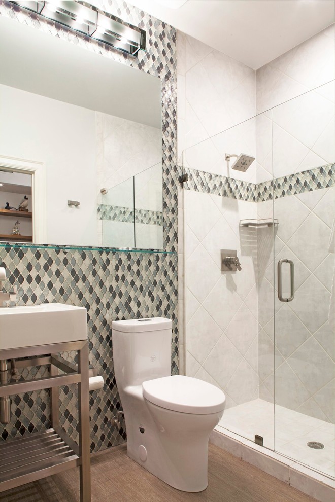 This is an example of a small classic bathroom in New York with an alcove shower, a one-piece toilet, a wall-mounted sink and a hinged door.