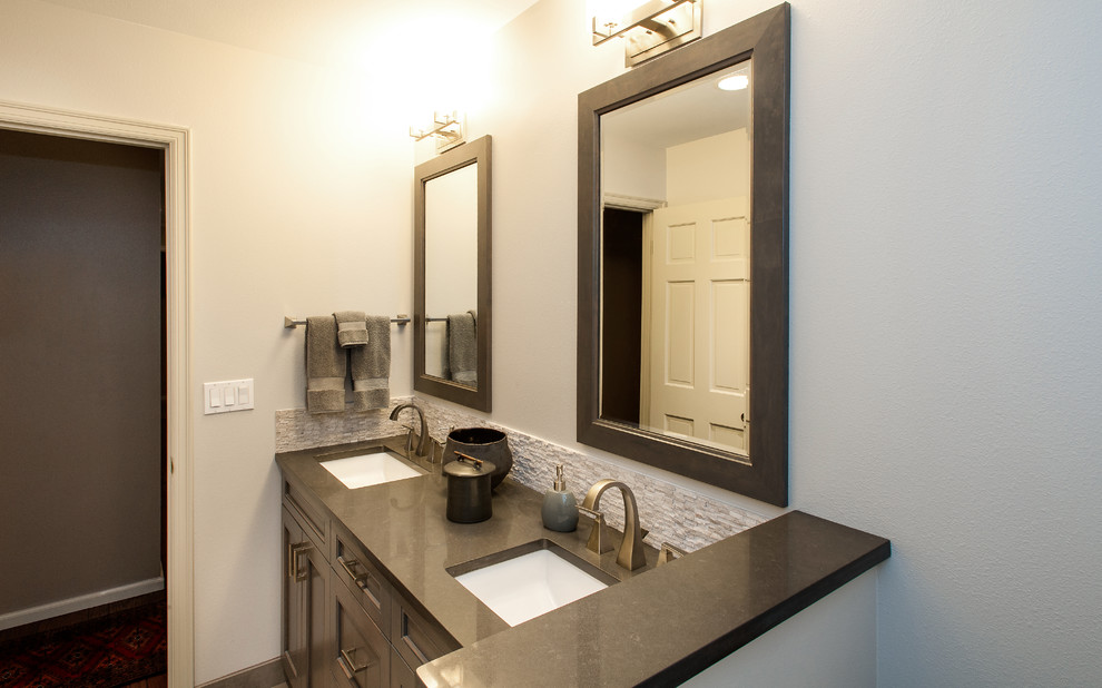 Réalisation d'une salle de bain principale tradition de taille moyenne avec un lavabo encastré, un plan de toilette en surface solide, un combiné douche/baignoire, un carrelage gris, un carrelage de pierre et un mur blanc.