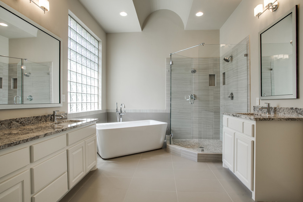 Exemple d'une grande salle de bain principale chic avec des portes de placard blanches, un plan de toilette en granite, une baignoire indépendante, une douche d'angle, un carrelage beige et des carreaux de céramique.