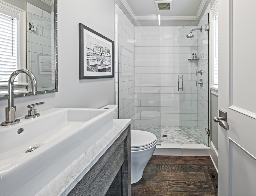 Design ideas for a large traditional shower room bathroom in Seattle with shaker cabinets, brown cabinets, an alcove shower, a one-piece toilet, white tiles, stone tiles, grey walls, dark hardwood flooring, a trough sink, marble worktops, brown floors and a hinged door.