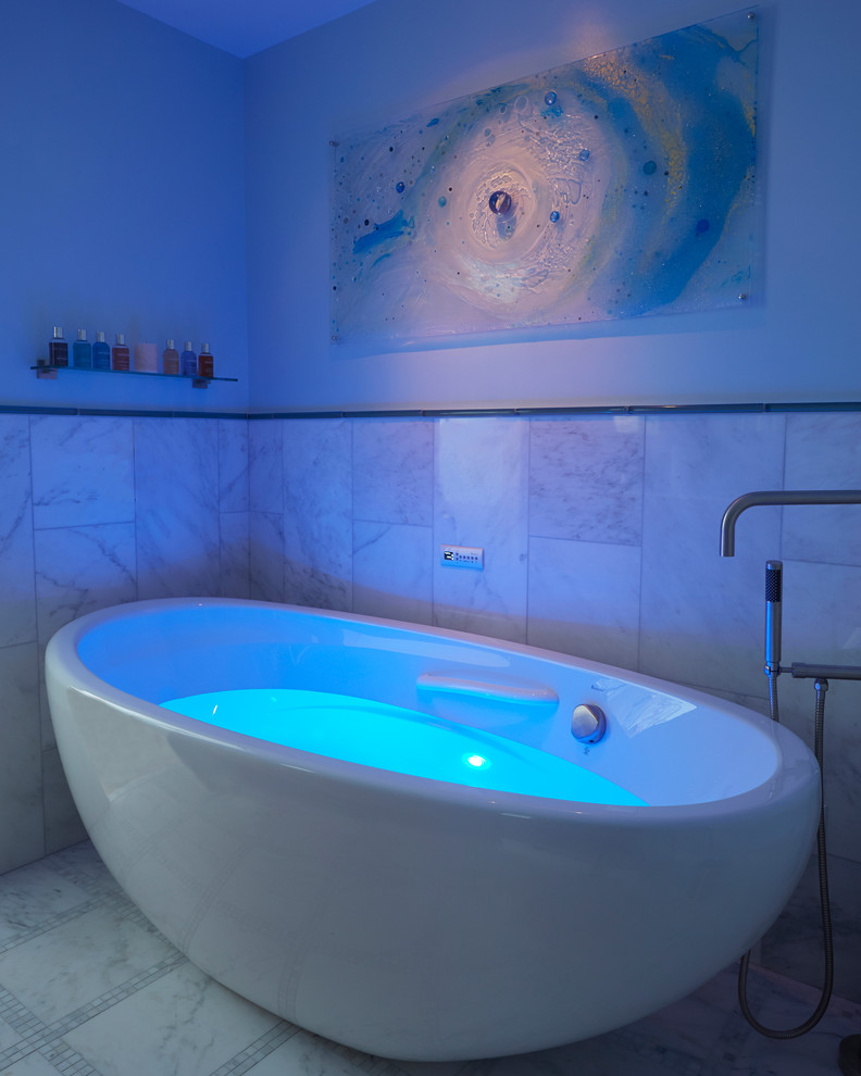 Exemple d'une salle de bain principale chic de taille moyenne avec une baignoire indépendante, un carrelage blanc, un mur bleu, un carrelage de pierre et un sol en marbre.