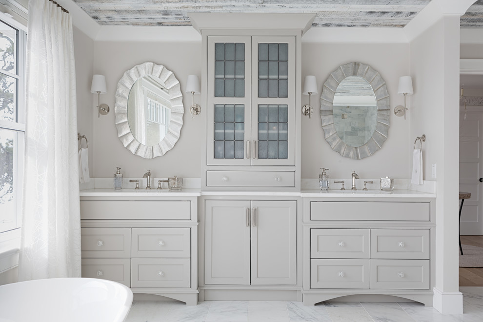 Inspiration för ett stort maritimt vit vitt en-suite badrum, med grå skåp, beige väggar, marmorgolv, marmorbänkskiva, grått golv, luckor med infälld panel, ett fristående badkar, en dusch i en alkov, ett undermonterad handfat och dusch med gångjärnsdörr