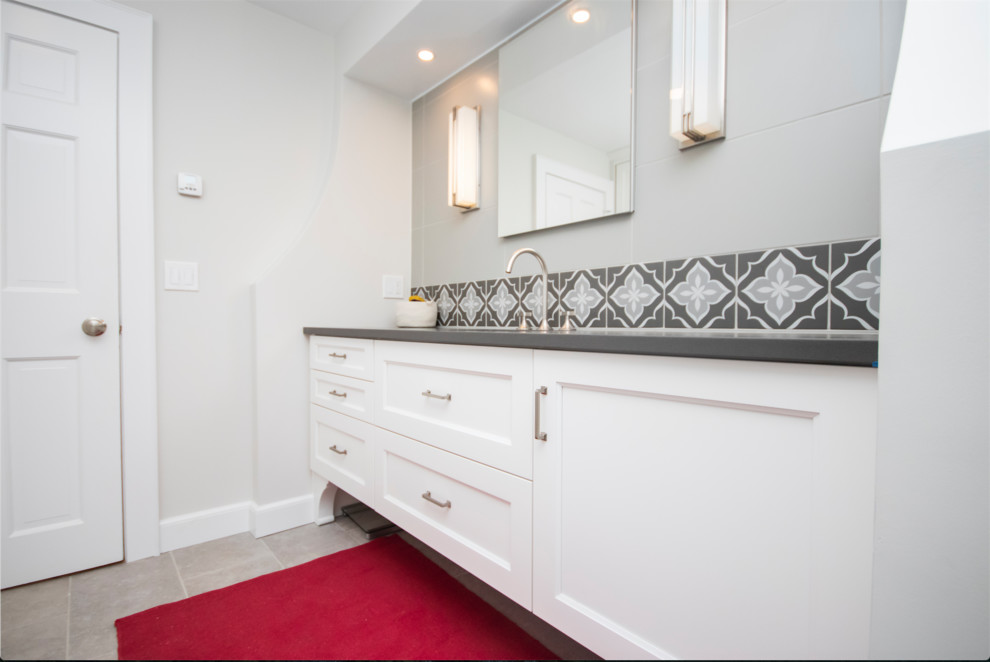 Пример оригинального дизайна: большая главная ванная комната в стиле неоклассика (современная классика) с фасадами с утопленной филенкой, белыми фасадами, угловым душем, раздельным унитазом, серой плиткой, керамической плиткой, серыми стенами, полом из керамической плитки, врезной раковиной, столешницей из искусственного кварца, серым полом, душем с распашными дверями и серой столешницей