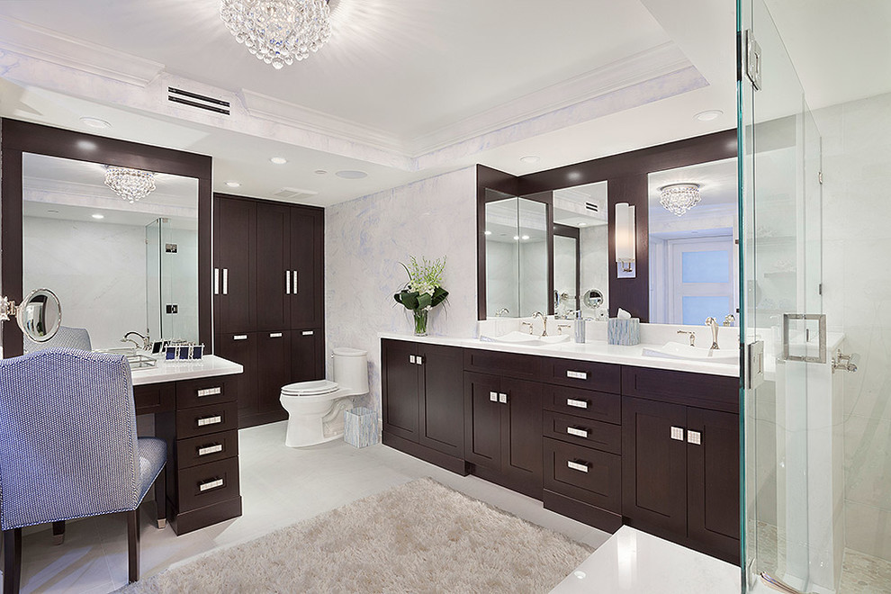 Example of a large transitional 3/4 white tile white floor alcove shower design in Miami with a drop-in sink, white walls, dark wood cabinets, recessed-panel cabinets, a two-piece toilet, solid surface countertops, a hinged shower door and white countertops