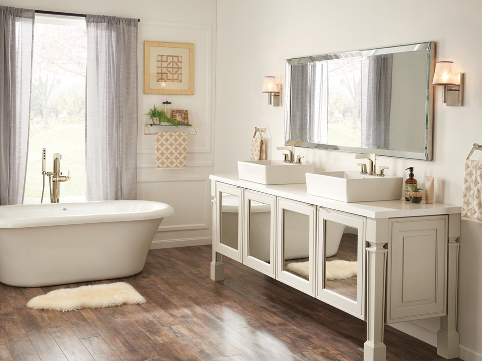 Huge transitional master medium tone wood floor and brown floor freestanding bathtub photo in Indianapolis with glass-front cabinets, beige cabinets, beige walls and a vessel sink