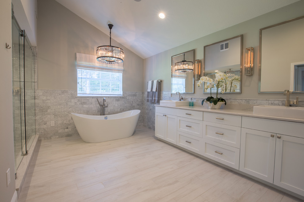 Design ideas for a medium sized classic ensuite bathroom in Tampa with shaker cabinets, white cabinets, a freestanding bath, an alcove shower, grey tiles, white tiles, stone tiles, beige walls, vinyl flooring and a vessel sink.