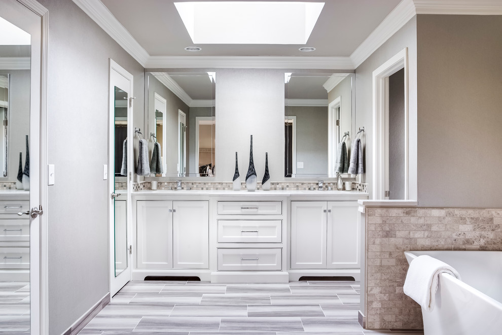 Пример оригинального дизайна: главная, серо-белая ванная комната среднего размера в стиле неоклассика (современная классика) с фасадами с утопленной филенкой, белыми фасадами, отдельно стоящей ванной, серыми стенами, полом из керамогранита, столешницей из искусственного кварца, плиткой мозаикой и бежевой плиткой
