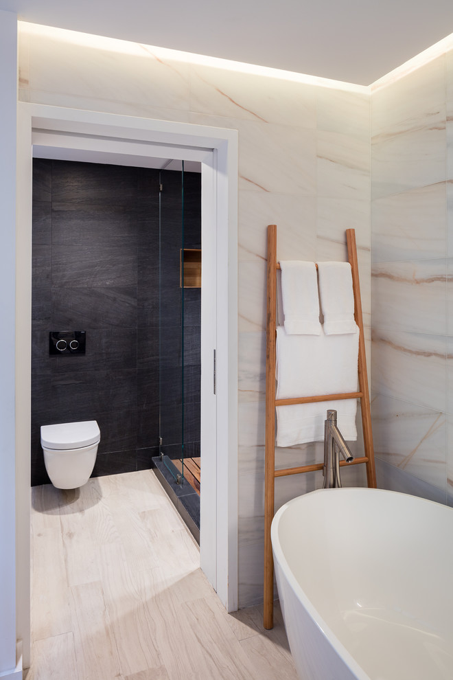 Пример оригинального дизайна: большая главная ванная комната в современном стиле с плоскими фасадами, темными деревянными фасадами, отдельно стоящей ванной, душем в нише, инсталляцией, белой плиткой, мраморной плиткой, черными стенами, паркетным полом среднего тона, подвесной раковиной, столешницей из искусственного кварца, бежевым полом, душем с распашными дверями и белой столешницей