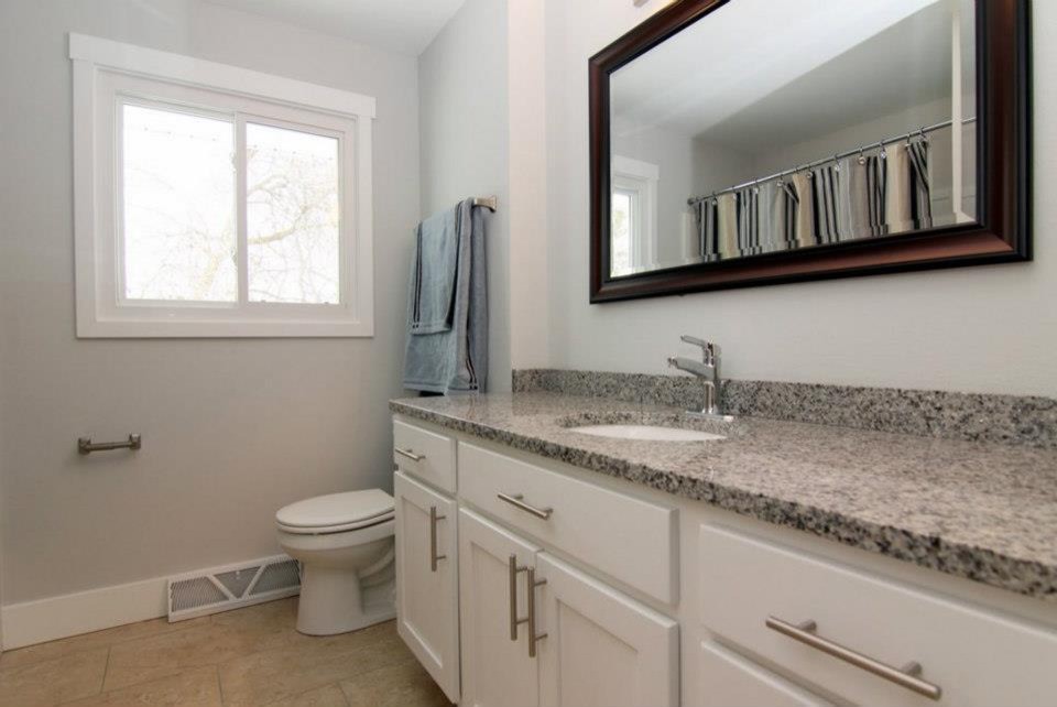 Medium sized traditional shower room bathroom in Wichita with shaker cabinets, white cabinets, an alcove bath, a shower/bath combination, a two-piece toilet, grey walls, travertine flooring, a submerged sink and granite worktops.