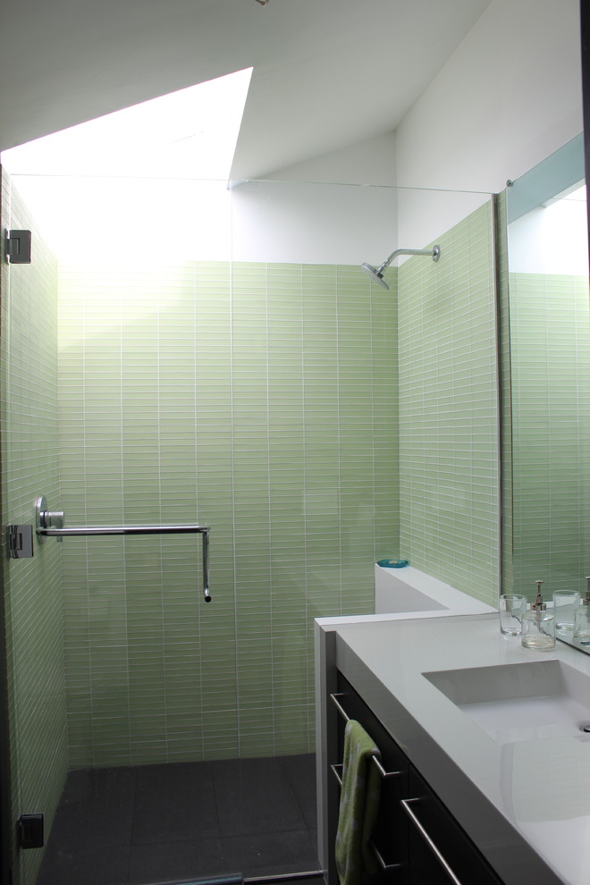 Foto på ett litet funkis vit badrum, med släta luckor, skåp i mörkt trä, en toalettstol med hel cisternkåpa, grön kakel, glaskakel, vita väggar, klinkergolv i porslin, ett integrerad handfat, svart golv och dusch med gångjärnsdörr