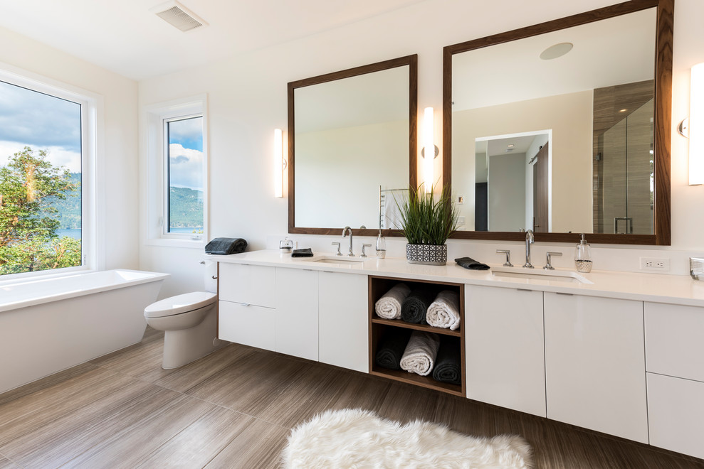 Ispirazione per una stanza da bagno contemporanea con ante lisce, ante bianche, vasca freestanding, pareti bianche, lavabo sottopiano, pavimento marrone, top bianco e due lavabi
