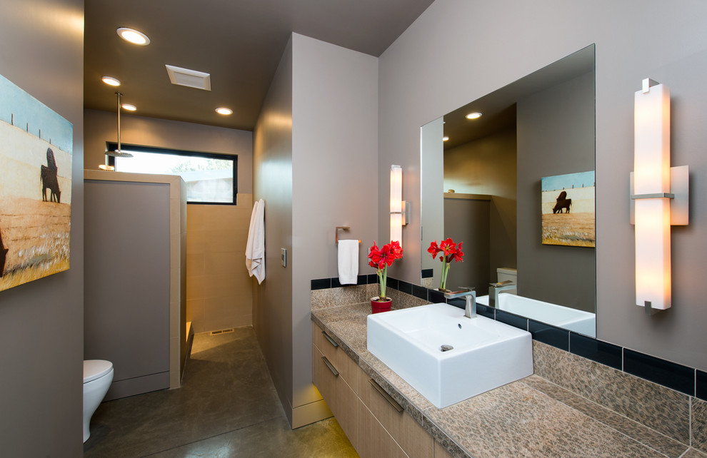 Example of a mid-sized trendy master concrete floor corner shower design in Other with a vessel sink, flat-panel cabinets, light wood cabinets, gray walls and a one-piece toilet