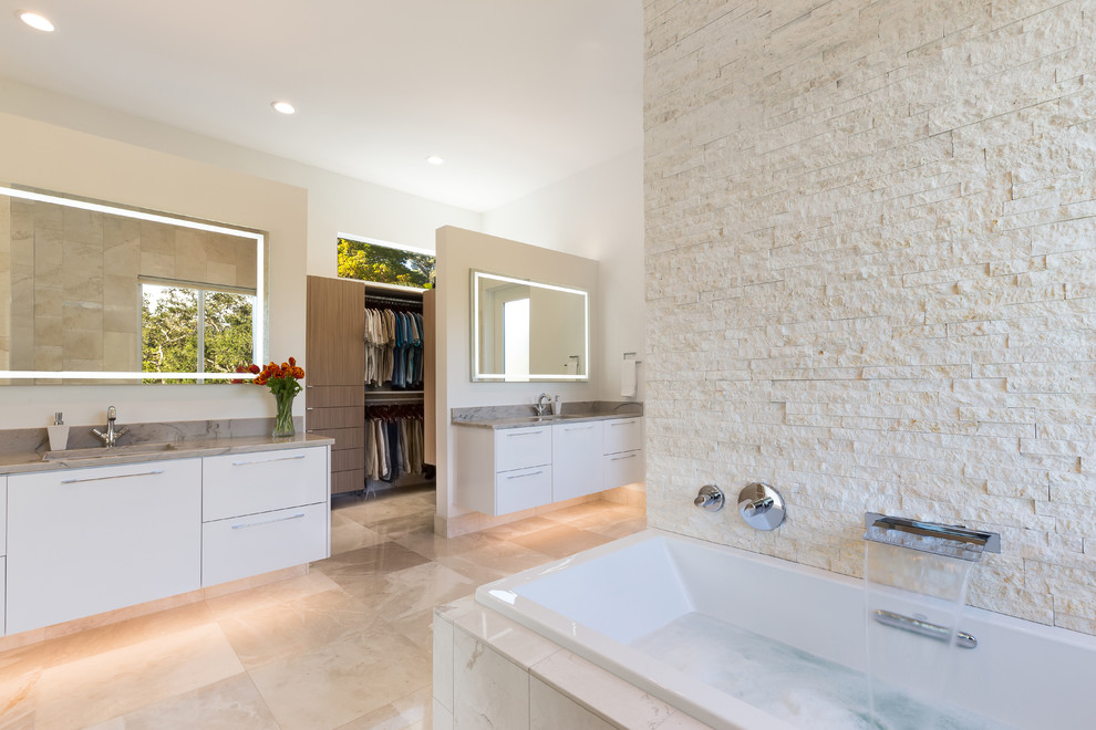 This is an example of a large contemporary ensuite wet room bathroom in Tampa with flat-panel cabinets, white cabinets, a japanese bath, a one-piece toilet, beige tiles, white walls, travertine flooring, a submerged sink, marble worktops, beige floors and an open shower.
